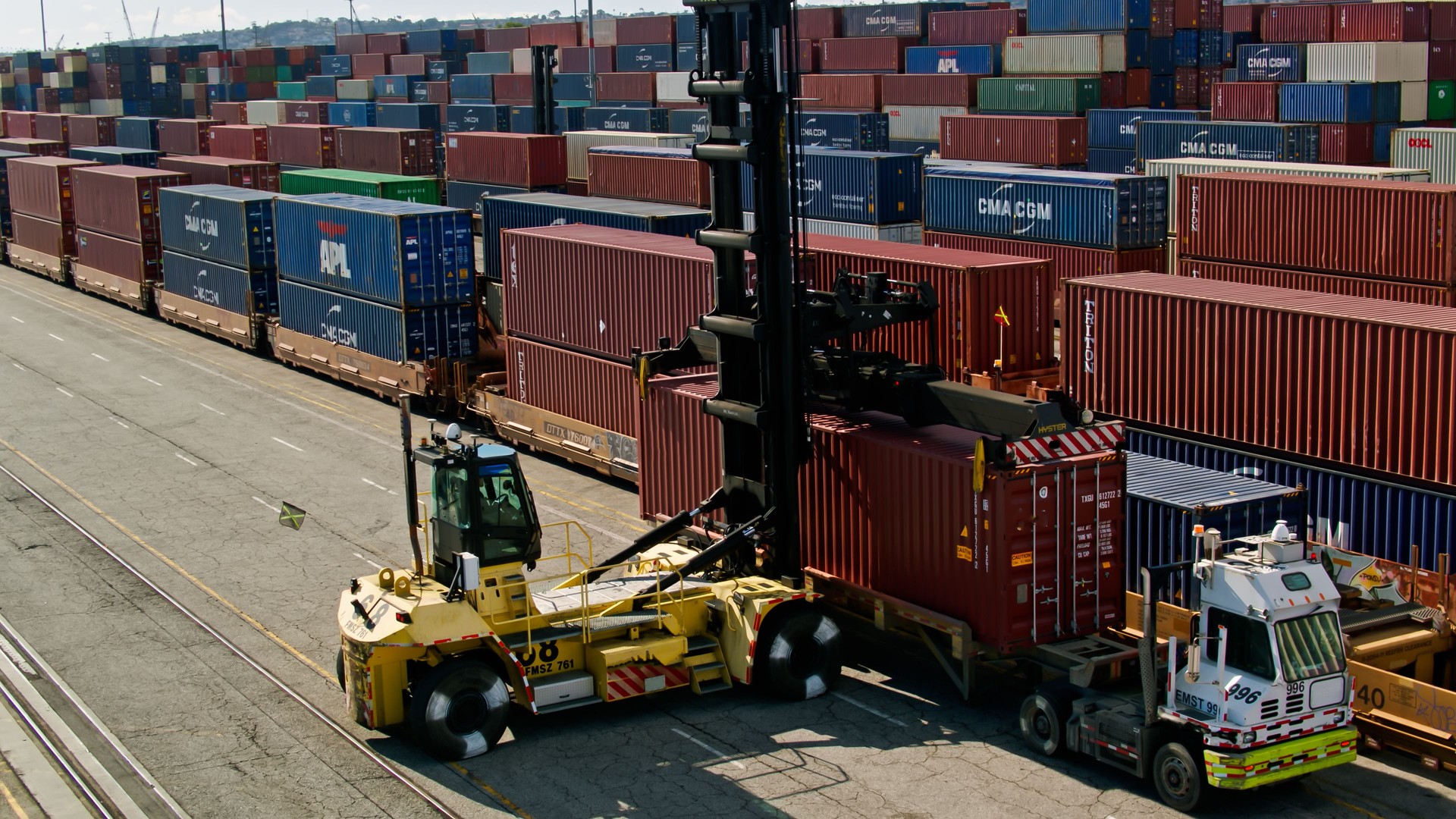 Top Handler Placing Shipping Container on Freight Train Car in Port of LA - Aerial